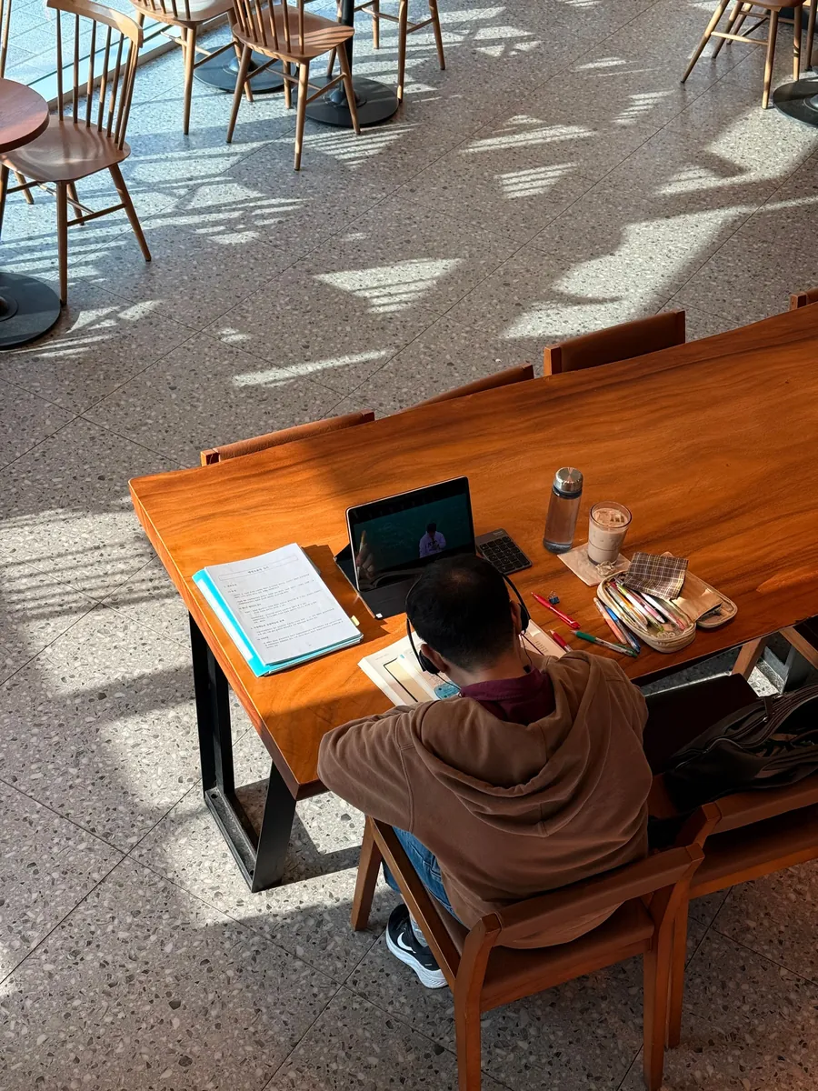 Learner studying with books and a laptop